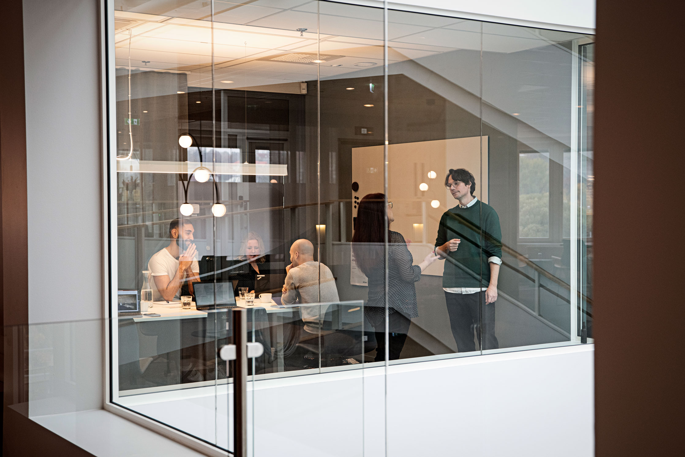 Man sieht von außen in ein Meetingraum in der sich eine Gruppe von Intrum Mitarbeiter befindet