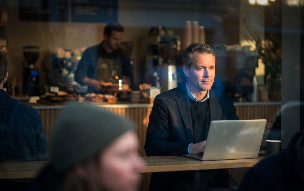 Mann mit einem Notebook sitzt im Cafe