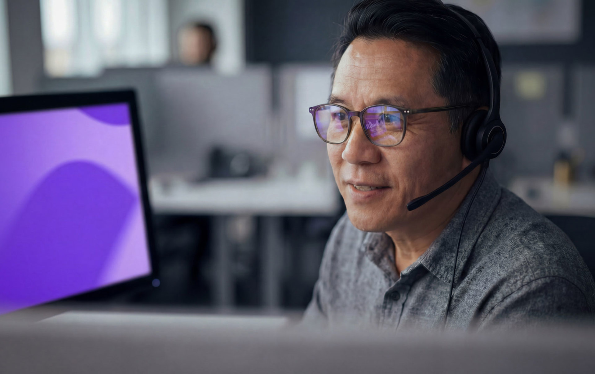 Ein Mann mit Headset sitzt an einem Monitor