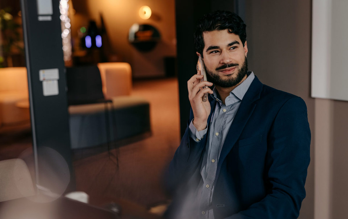 Ein Mann sitzt im Büro und telefoniert mit seinem Smartphone